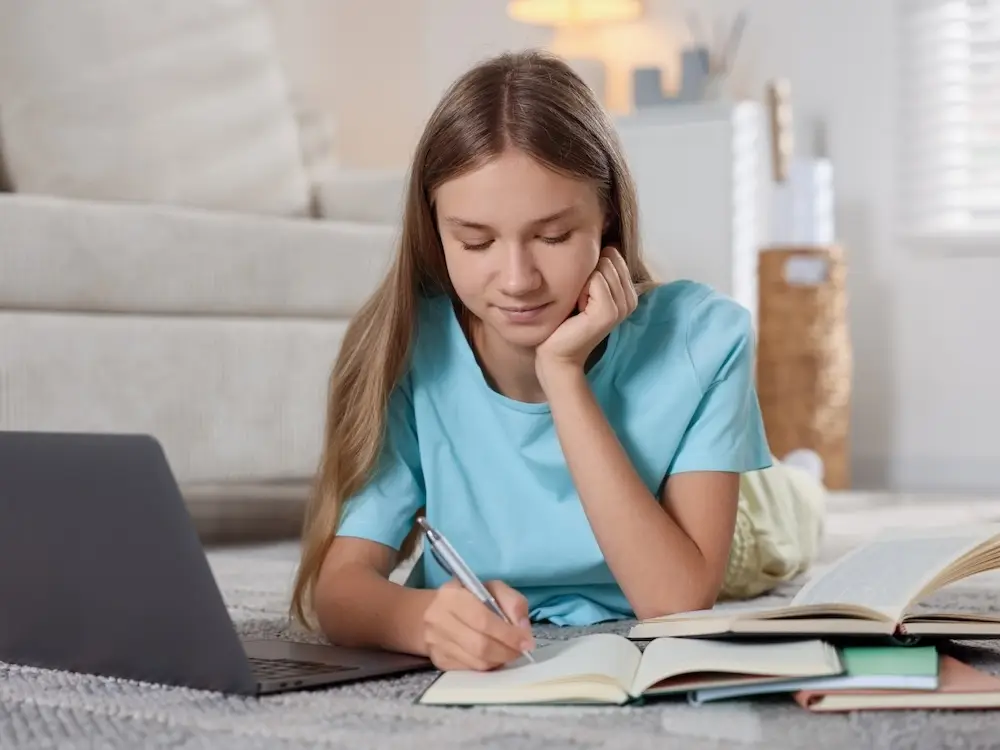 A teenage girl with anxiety is happily and confidently completing a difficult school assignment.