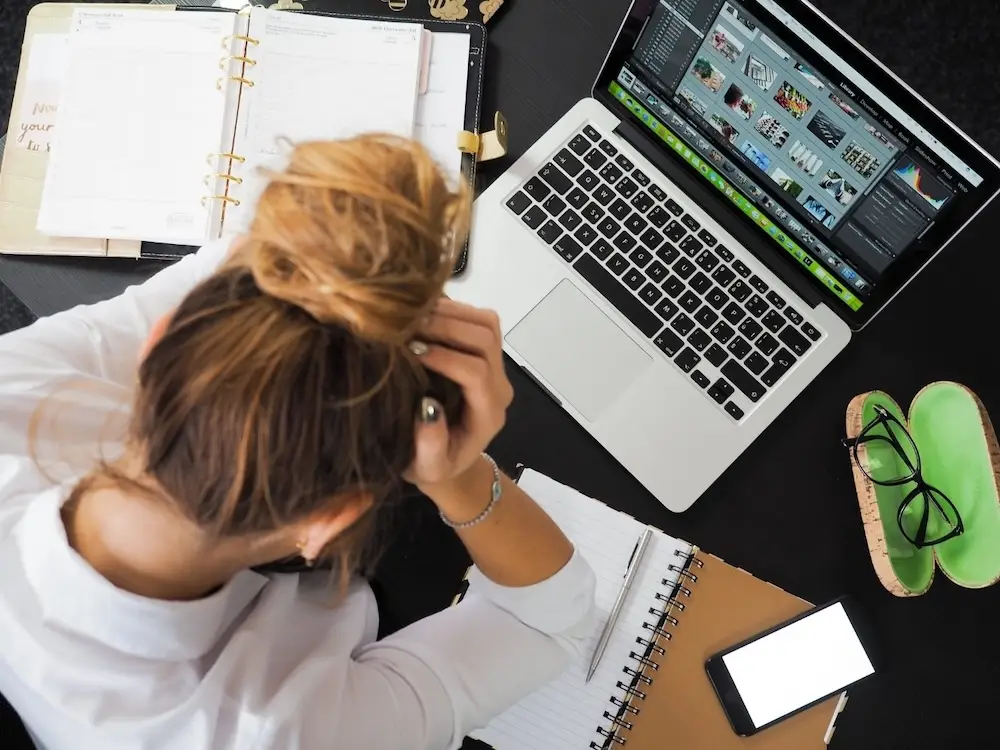 An adult woman is anxious and overwhelmed with her workload and her ADHD makes it difficult to even begin her work.